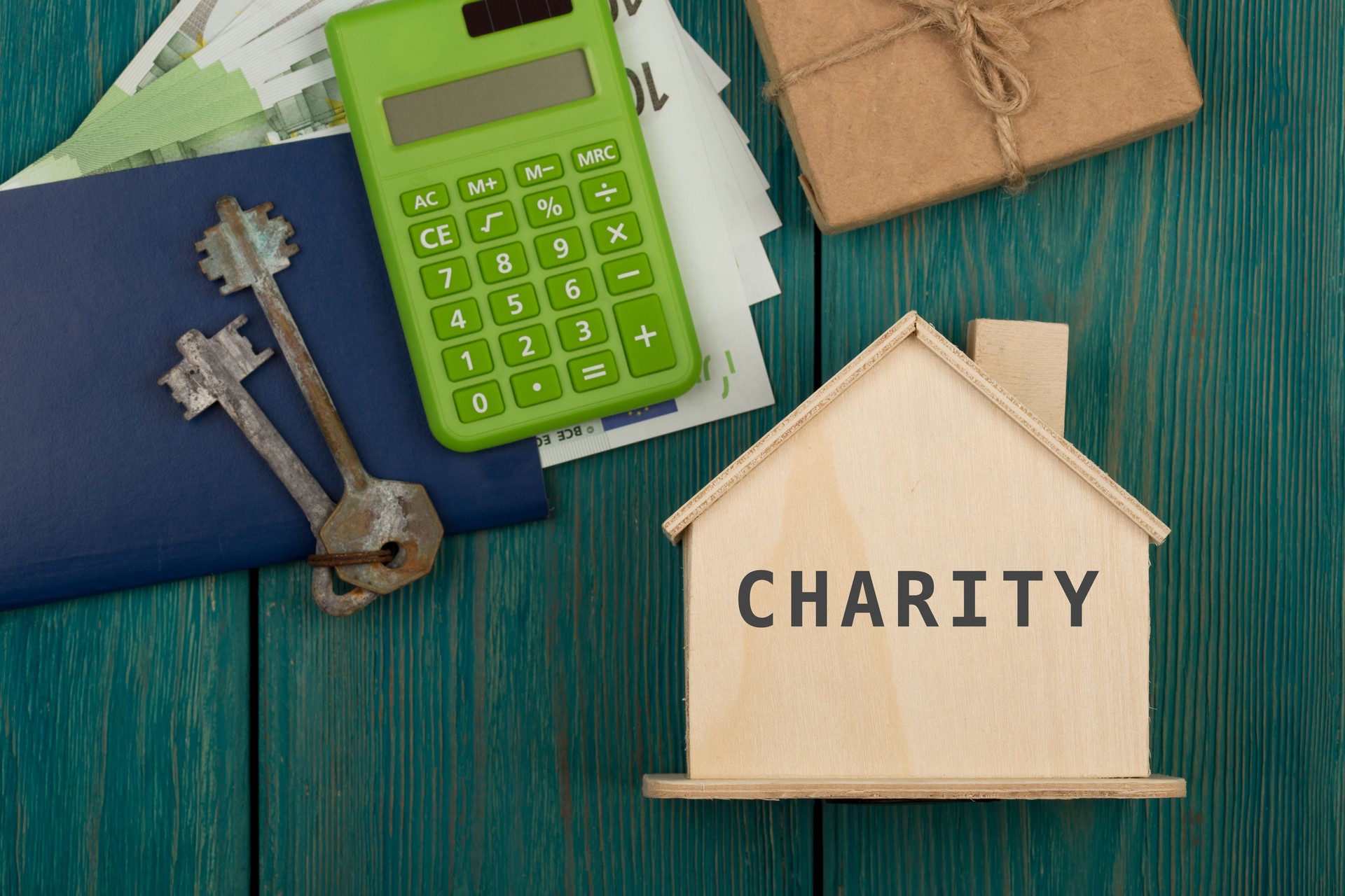 Little house with text "Charity", keys, calculator, passport, money